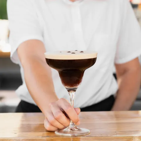 Camarero sirviendo un espresso martini en la barra de Aqua