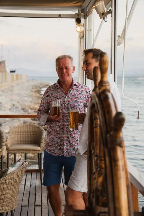 Dos amigos charlando con una cerveza en la terraza de Aqua