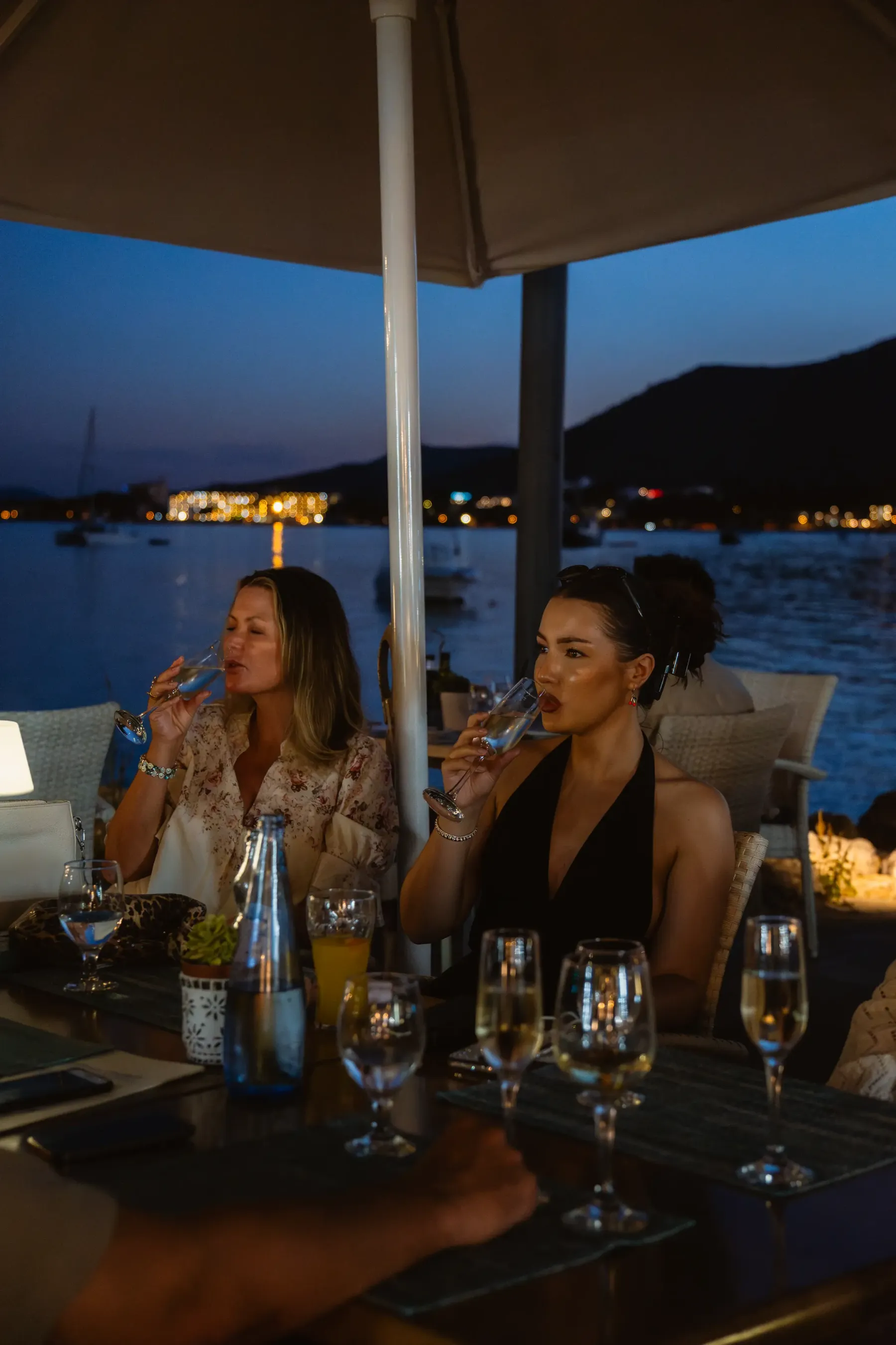 Dos amigas brindando de noche con las luces del puerto de Alcudia