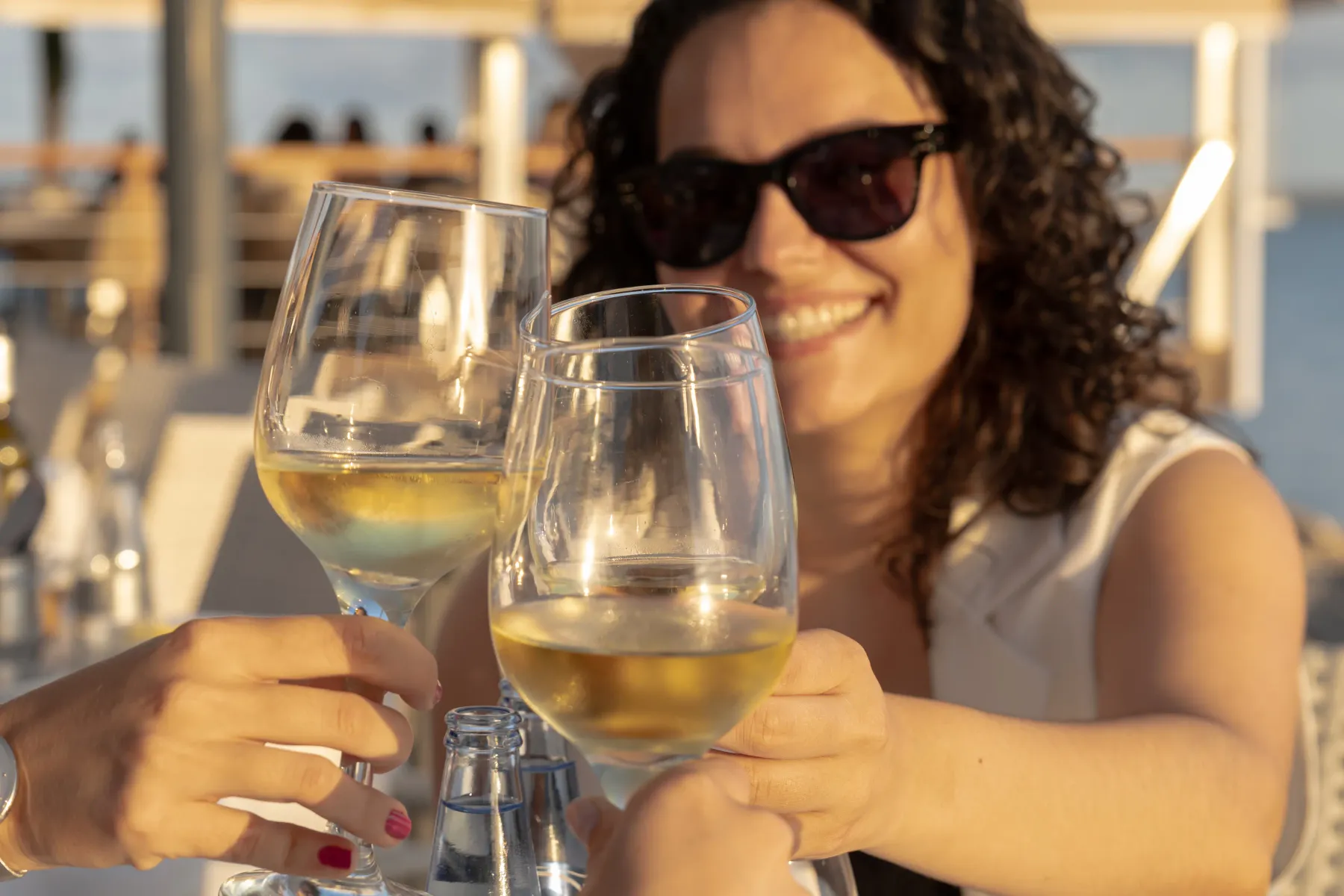 Clienta con gafas de sol brindando con vino blanco