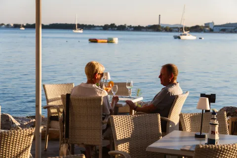 Clientes cenando al atardecer en la terraza sobre el mar
