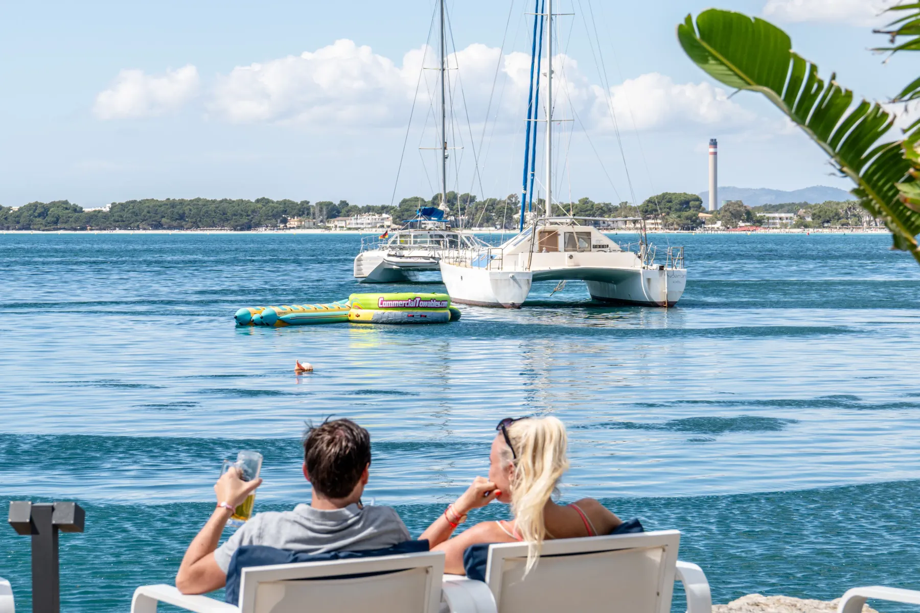 Clientes tomando algo frente a un catamarán en la bahía de Alcudia
