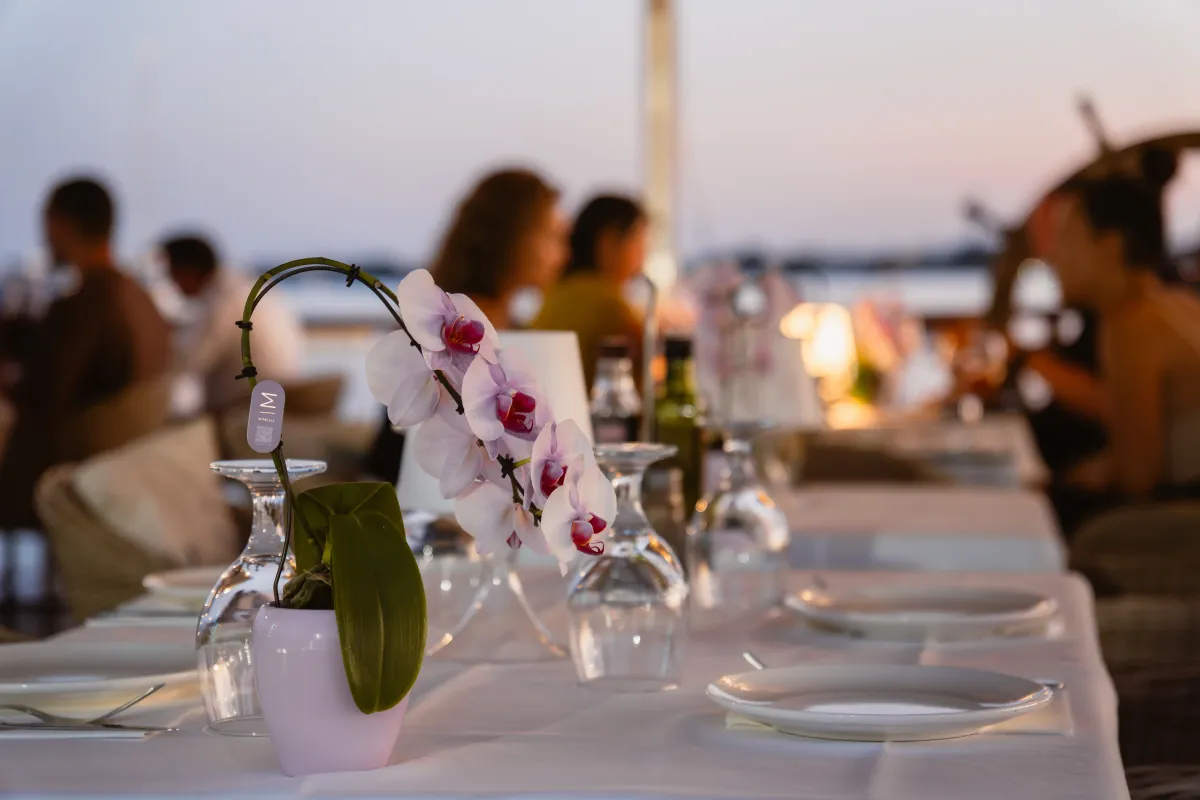 Mesa con orquídea y comensales al fondo durante la cena