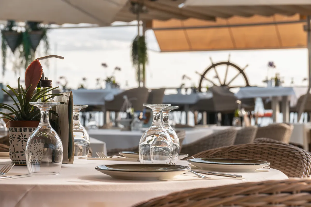 Mesas preparadas en la terraza con el timón de barco al fondo