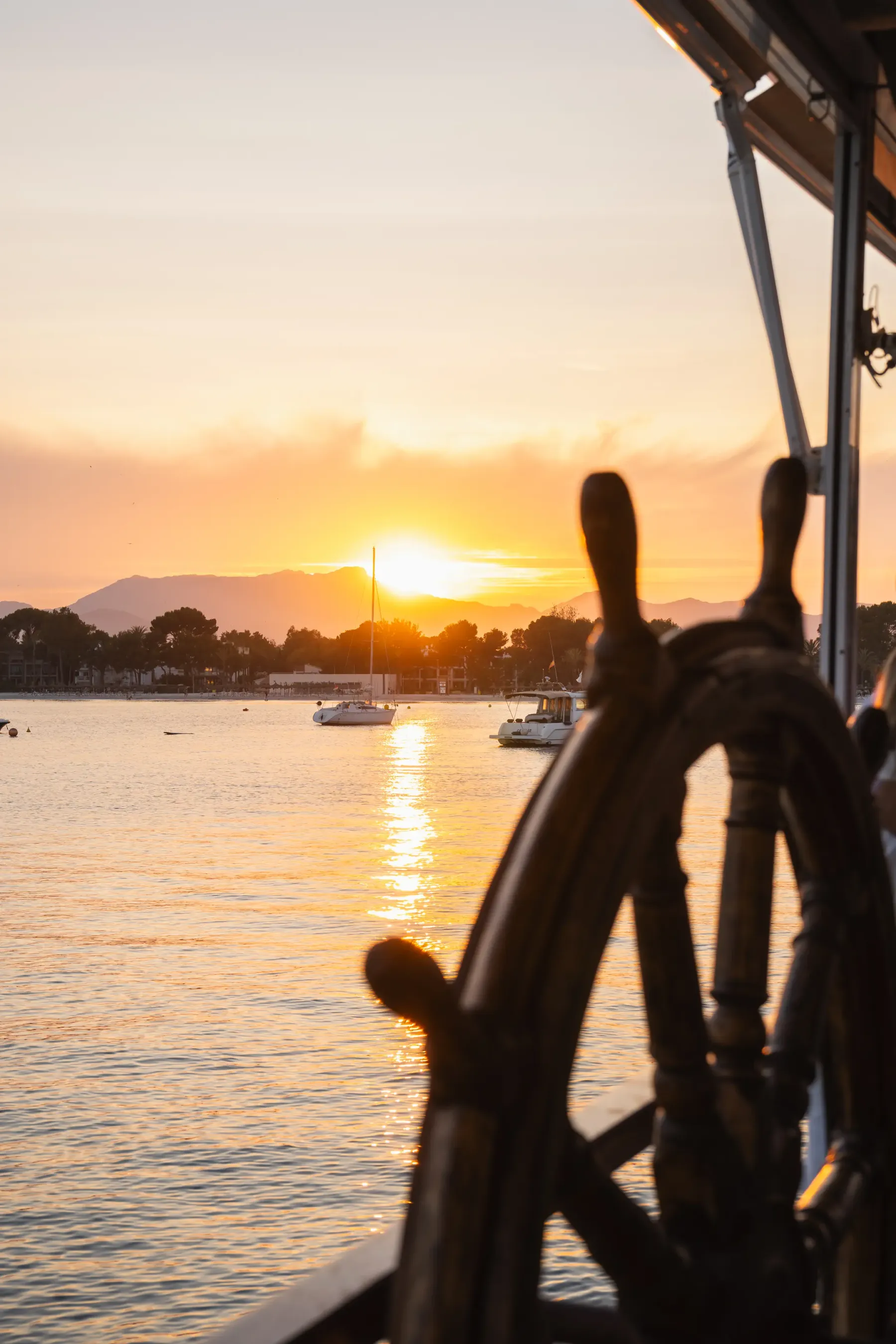 Timón de barco recortado sobre el atardecer de la bahía de Alcudia