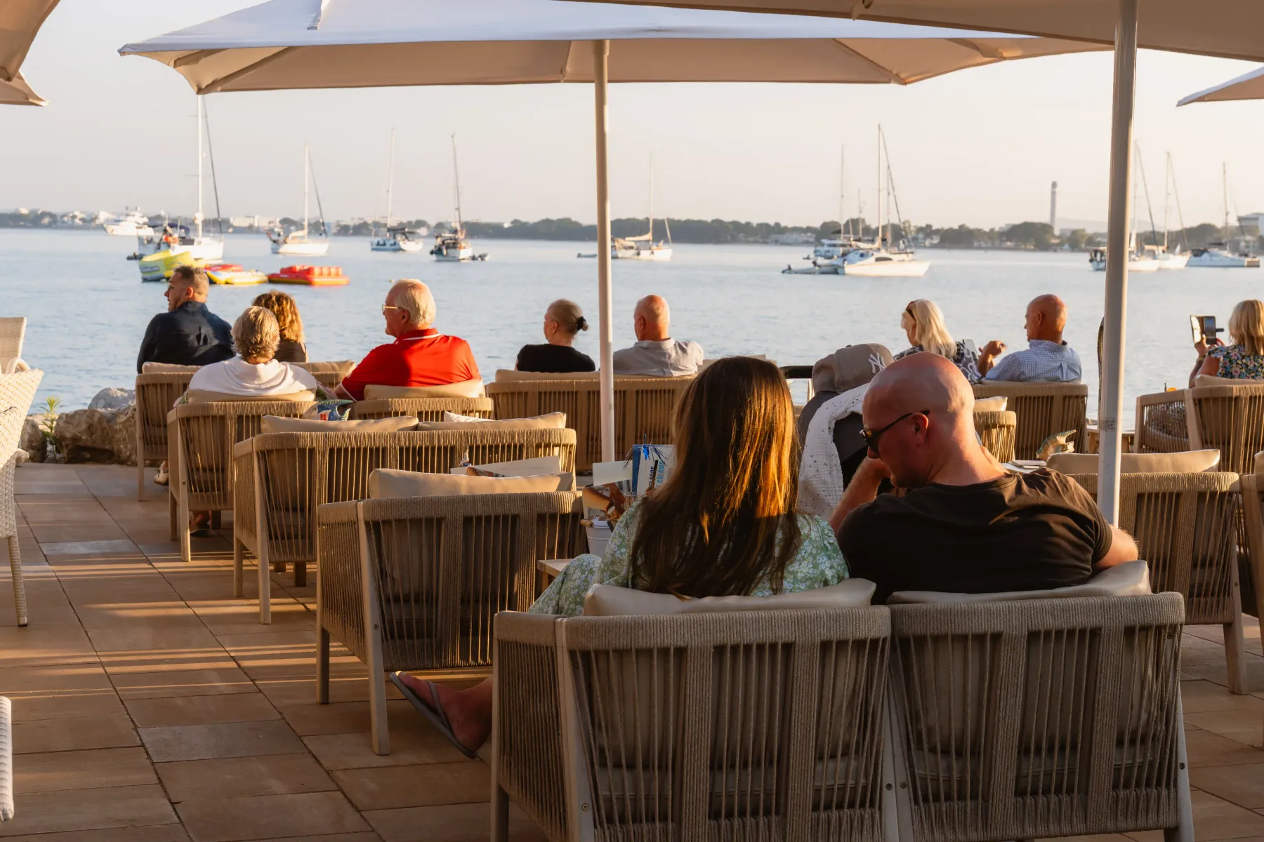 Terraza de Aqua con sombrilla y clientes frente al mar