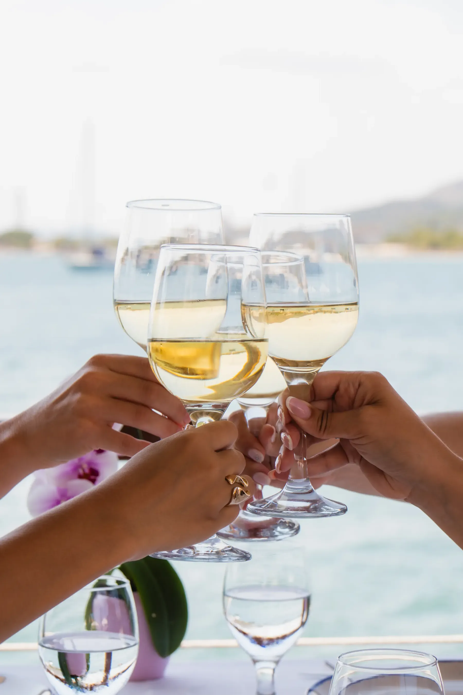 Brindis con tres copas de vino blanco frente al Mediterráneo